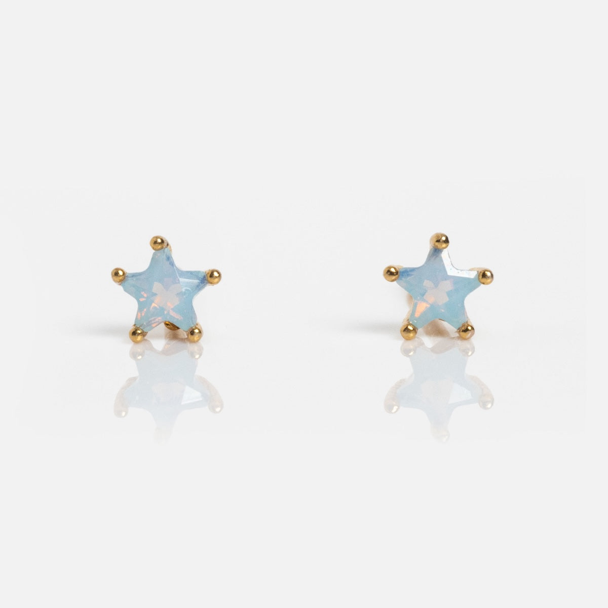 Milky Blue Star Studs: gold-trimmed, star-shaped earrings with a milky blue, slightly translucent center, shown on a white background.
