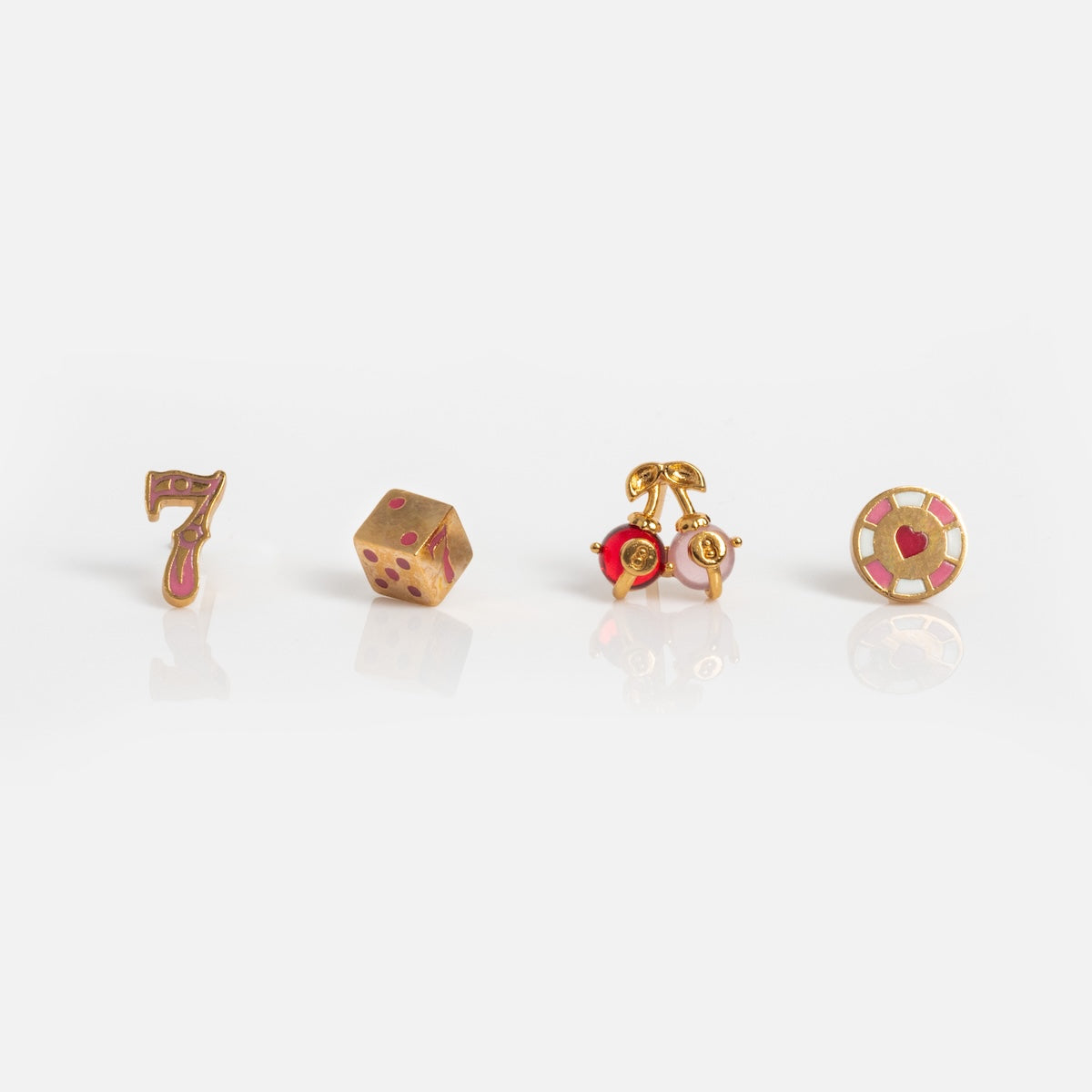 The Feeling Lucky Stud Set features four small gold pins—a red-and-gold number seven, a gold die with red dots, gold cherries, and a casino poker chip—displayed on a plain white background, perfect for your own lucky ear stack.