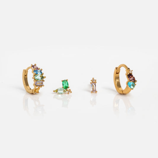 The Flora and Fauna Earring Set features gold-plated huggie hoops with multicolored gemstones and three coordinating stud earrings, displayed on a white reflective surface.