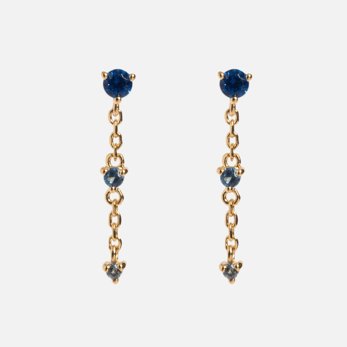 The Celebration Ombre Birthstone Drop Studs are 14k gold plated chain earrings with a round blue gemstone at the top and two smaller blue stones on the dangle, offering an elegant touch of personalized jewelry.