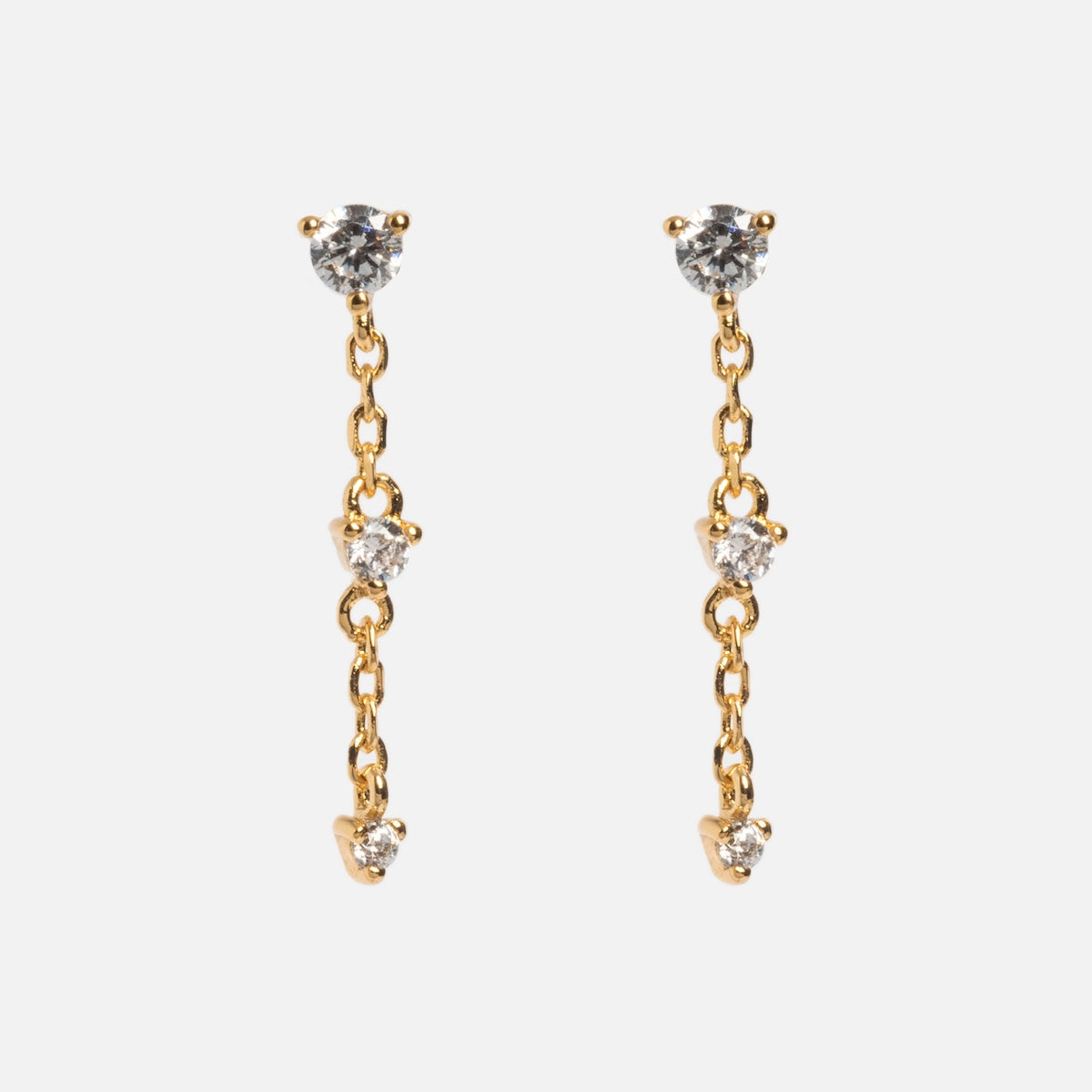 The Celebration Ombre Birthstone Drop Studs are 14k gold plated earrings with three round clear gemstones set vertically on a gold chain, shown against a plain white background.