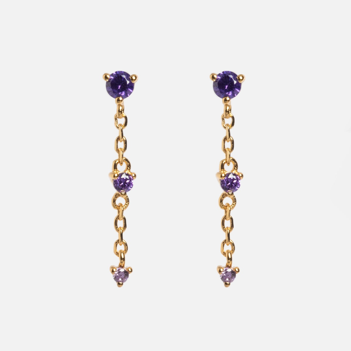 The Celebration Ombre Birthstone Drop Studs feature three evenly spaced round purple gemstones on each 14k gold plated drop earring, shown against a white background for an elegant look.
