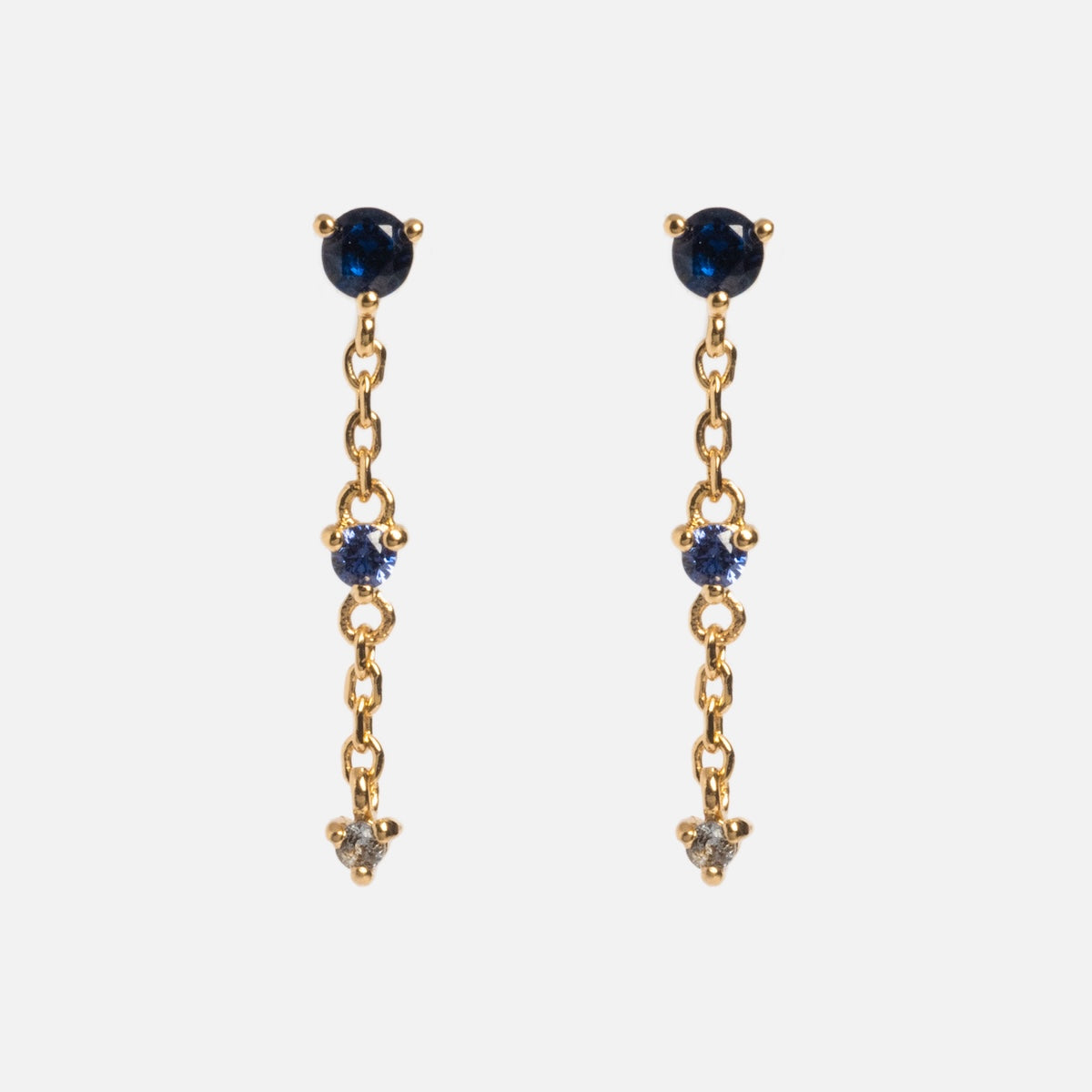 The Celebration Ombre Birthstone Drop Studs are 14k gold plated chain earrings with three vertically set gemstones on each—dark blue at the top, light blue in the middle, and clear at the bottom for an ombre effect.