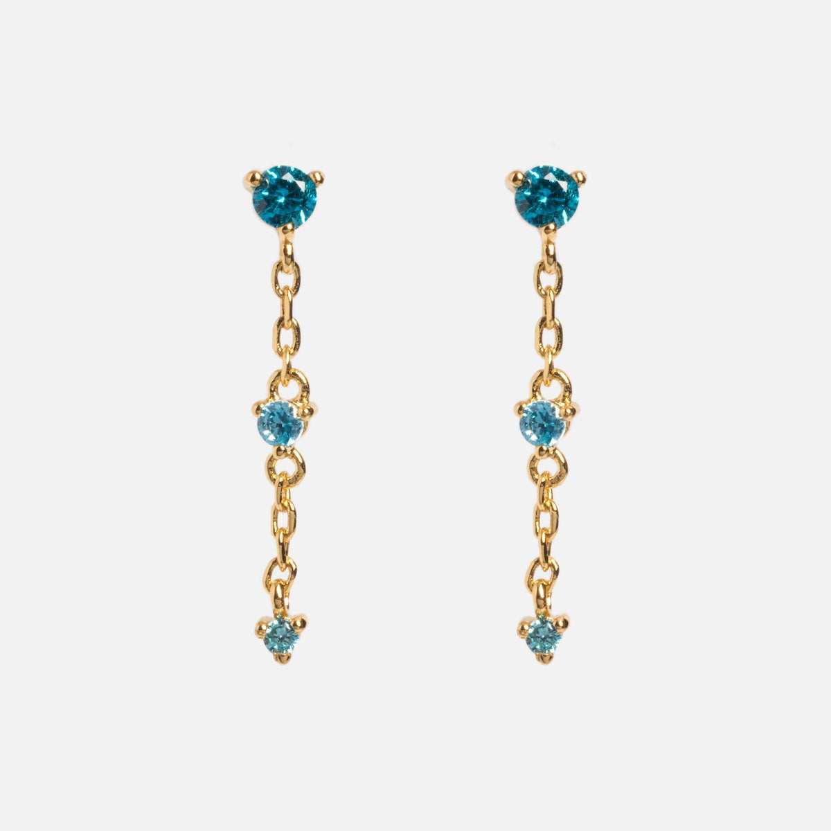 The Celebration Ombre Birthstone Drop Studs are 14k gold-plated dangle earrings, each featuring three round blue gemstones linked by delicate gold chains—ideal for those seeking personalized jewelry style.