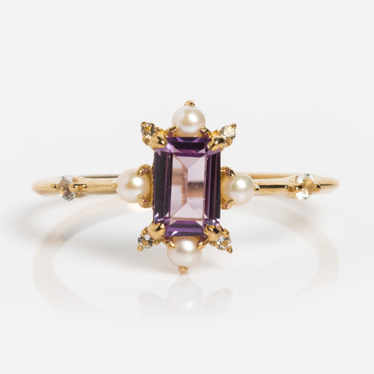 The Solid Gold 2025 June Capsule Alexandrite and Pearl Statement Set features a rectangular purple alexandrite center, pearls, and diamonds on a plain gold band. Includes a free gift. Displayed on a white background.