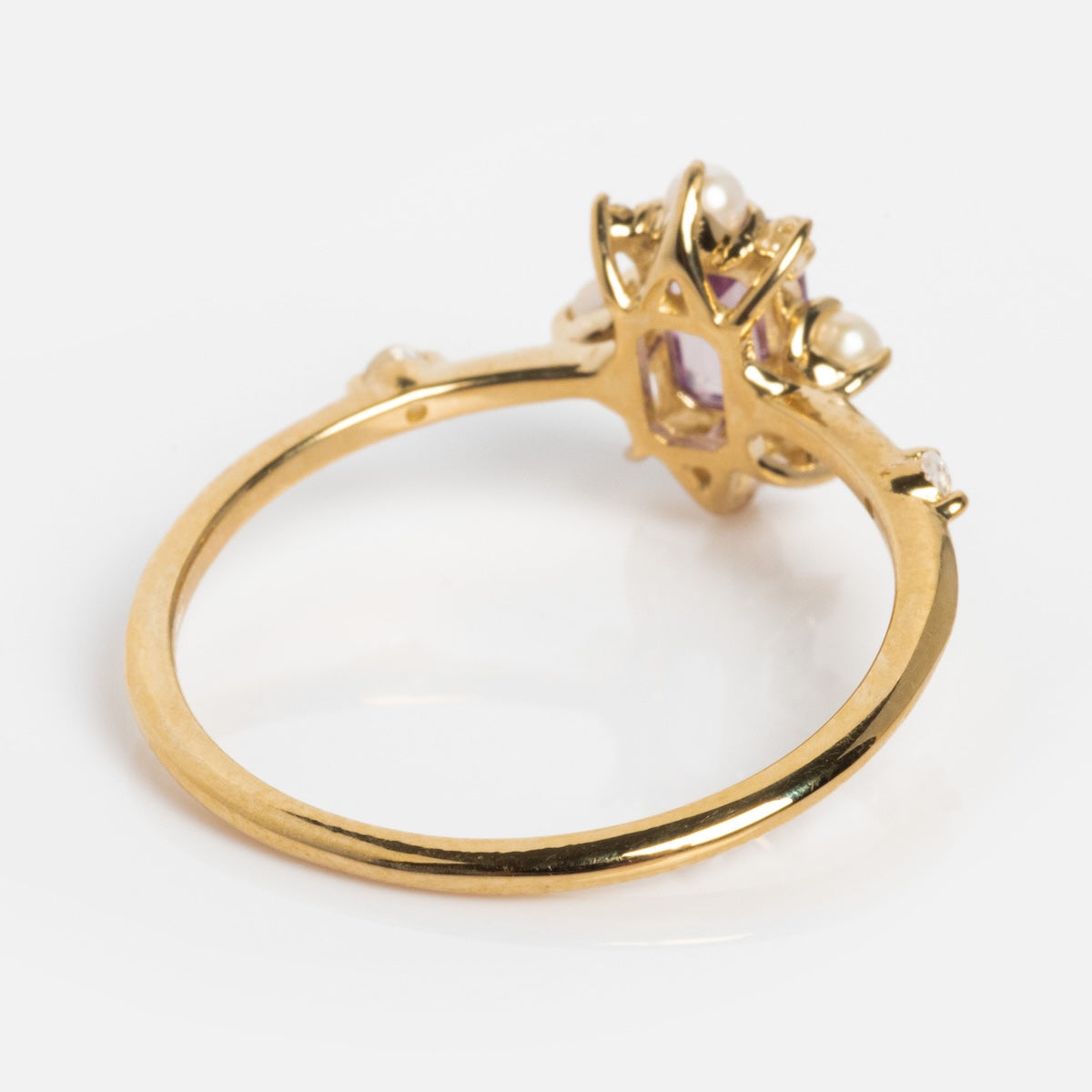 The Solid Gold 2025 June Capsule Art Deco Alexandrite and Pearl Statement Ring features a thin gold band, a central purple alexandrite stone, and pearl accents in an intricate art deco design, all pictured on a white background.