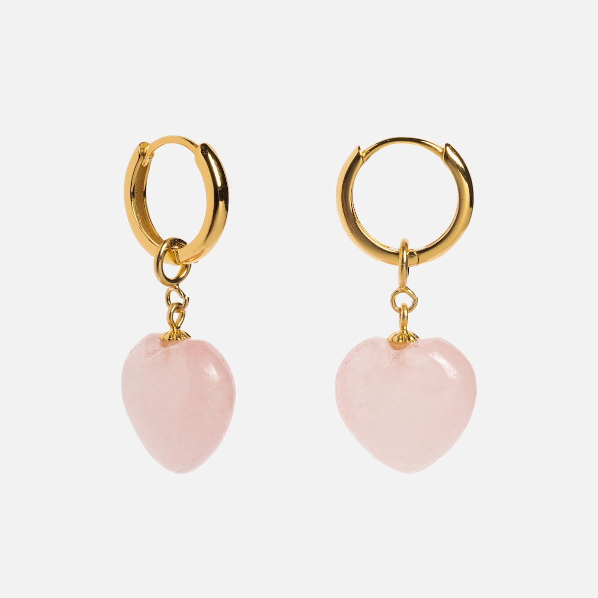 The Quartzite Heart Earrings are gold huggie hoops with dangling pink heart-shaped charms, shown against a plain white background.