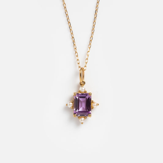 The Solid Gold 2025 June Capsule Vintage Inspired Alexandrite and Pearl Pendant Necklace features a rectangular purple alexandrite accented with small white pearls at each corner, shown against a plain white background.