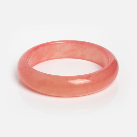 A Pink Quartzite Bangle, ideal for stacking with other bracelets, is elegantly displayed on a white background.