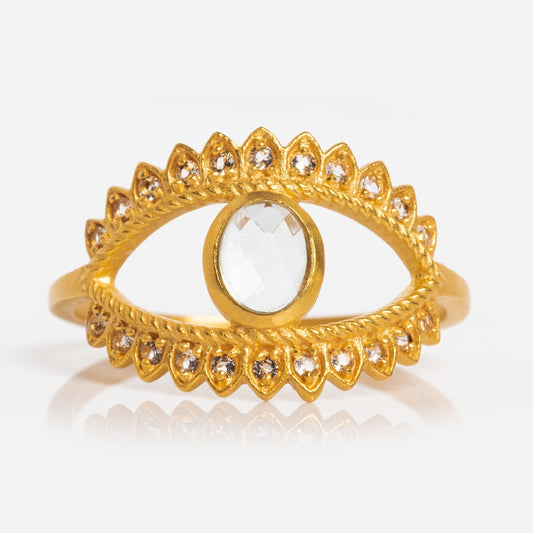 The Fancy Blue Topaz Eye Ring features a central round blue topaz surrounded by sparkling stones on a white background, offering stylish protection and elegance to any look.