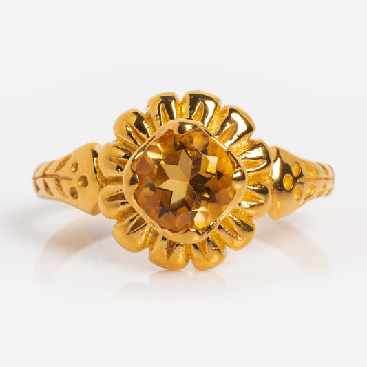 The Bloom Solitaire Ring in yellow gold vermeil showcases a central yellow-orange faceted citrine gemstone, accented by petal-inspired gold details and a textured band.