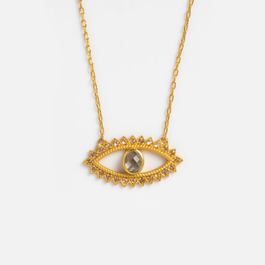 The Eye Blue Topaz Necklace features a faceted blue topaz eye pendant bordered with sparkling stones on a delicate 18k yellow gold plated chain—an elegant protection necklace displayed against a white background.