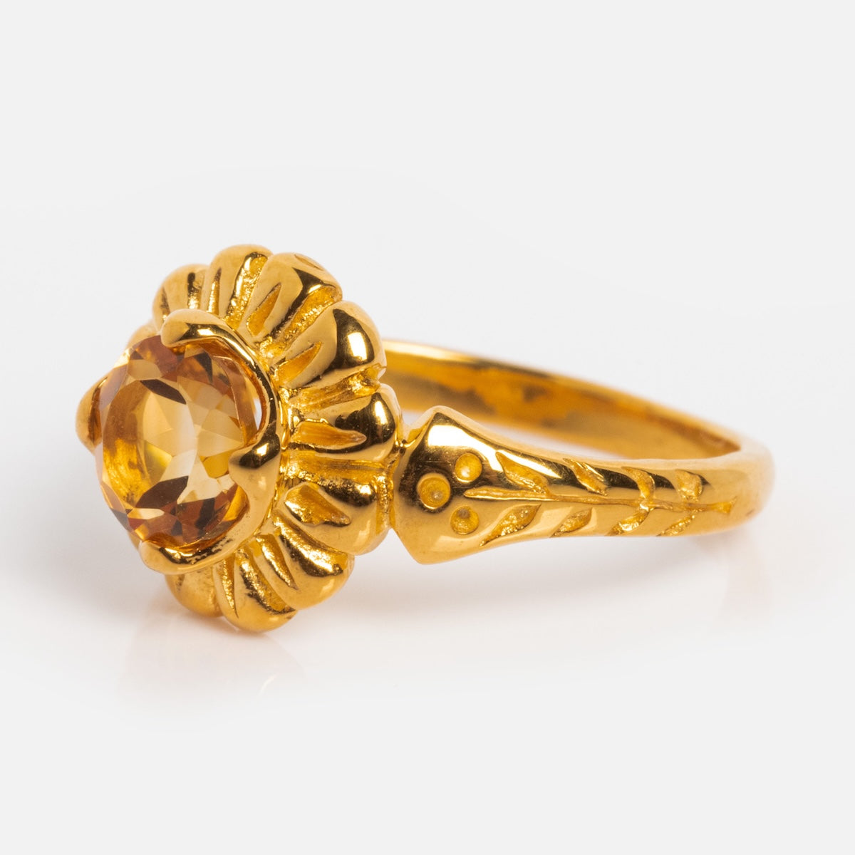 The Bloom Solitaire Ring showcases a floral-inspired design with a round citrine center stone on a textured yellow gold vermeil band featuring decorative engravings.