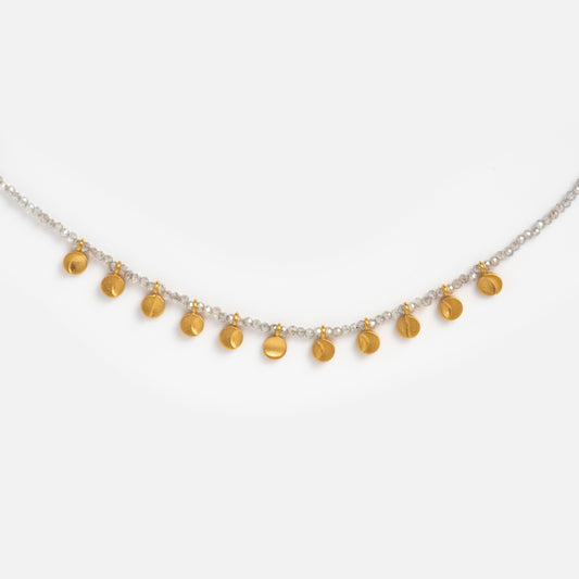 The Mystical Moonlight Necklace features a delicate gold-plated chain adorned with small white beads and evenly spaced gold coin charms, evoking moon phases, shown on a plain white background.