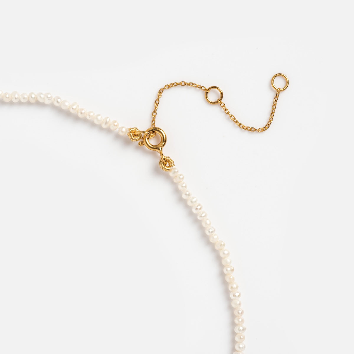 The Vermeil Delicate Pearl Chain features small white freshwater pearls and an adjustable gold chain with circular links and a gold clasp, shown close-up on a white background.