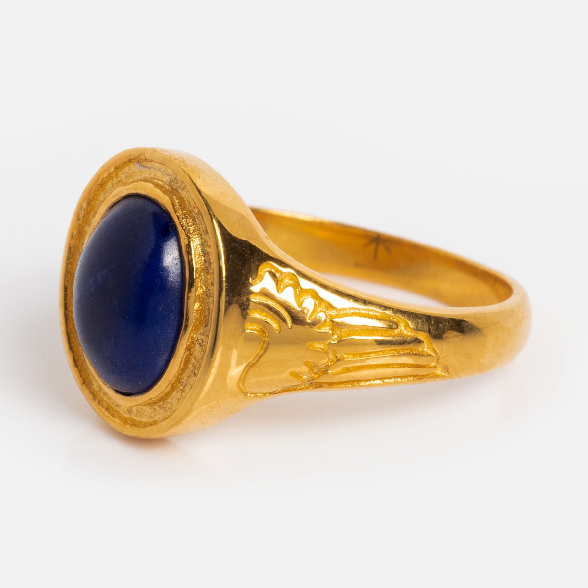 The Astral Ring is a gold vermeil ring featuring a round, deep blue Lapis stone at the center and wing engraving on the band, shown against a plain white background.
