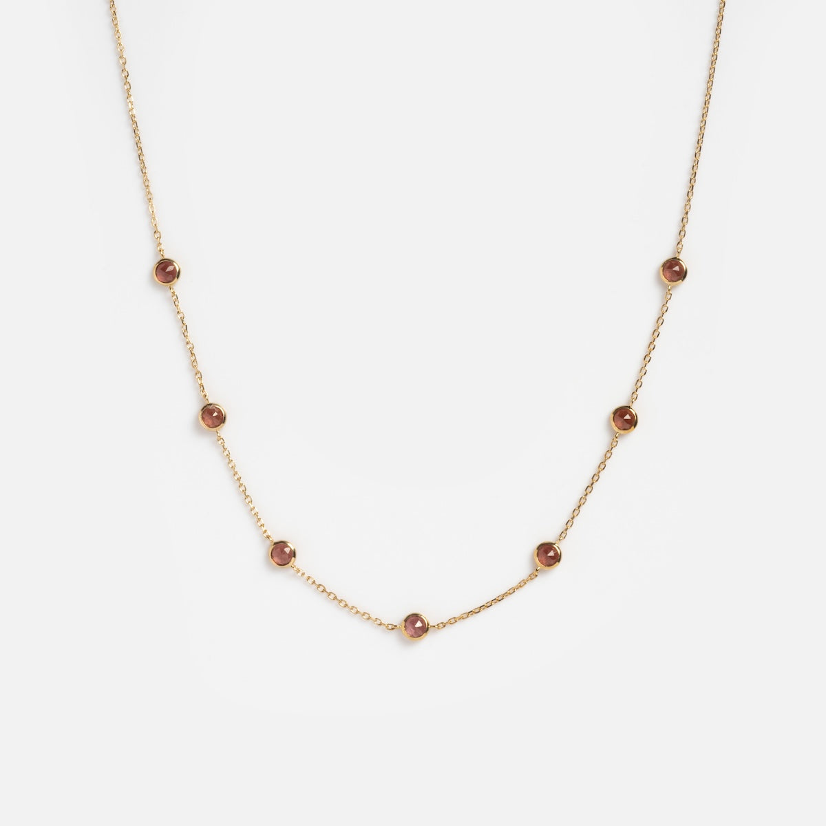 The Solid Gold Birthstone Station Necklace Sample is a delicate 9k yellow gold necklace with evenly spaced small round lab-created gemstones on a fine chain, shown against a plain white background.