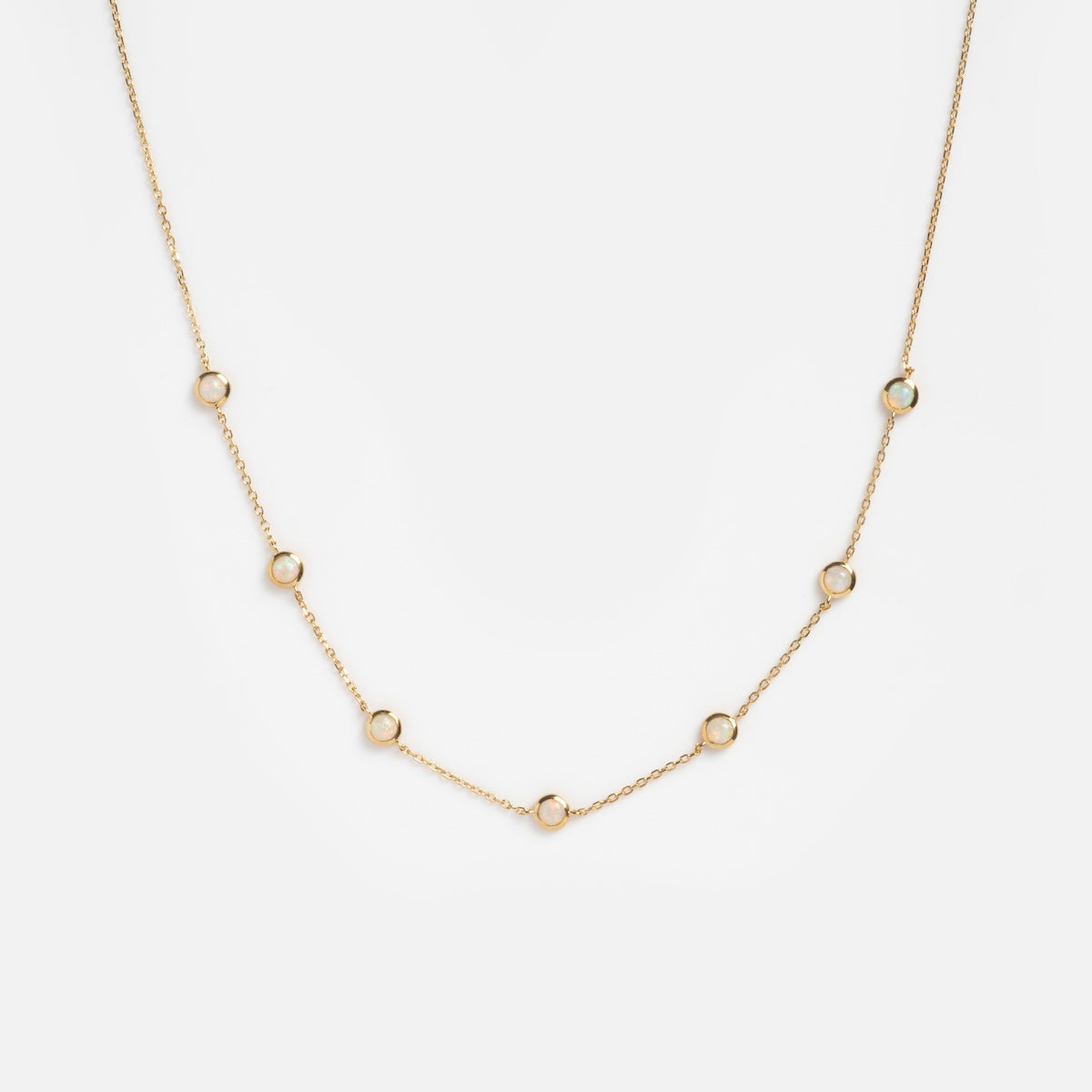 The Solid Gold Birthstone Station Necklace Sample is a delicate 9k yellow gold chain featuring seven evenly spaced small circular loops, shown on a plain white background.