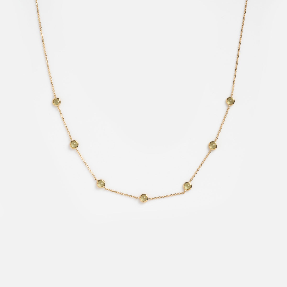 The Solid Gold Birthstone Station Necklace Sample is crafted in 9k yellow gold and features small, round lab-created gemstones in delicate bezel settings, evenly spaced along the chain and displayed on a white background.