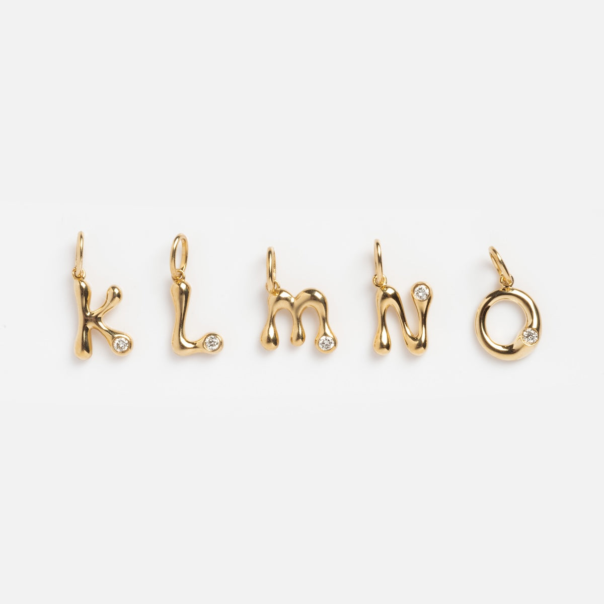 The Solid Gold Diamond Initial Charm Sample features five 9k yellow gold pendants shaped as K, L, M, N, and O, each accented with a 2 mm lab-created diamond and displayed on a white background.