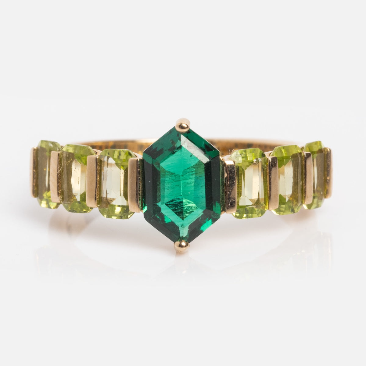 The 14k Emerald & Peridot Ring Sample Size 7 showcases a large emerald-cut lab-created emerald at the center with rectangular green peridots on each side, all set in solid yellow gold against a white background.