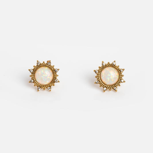 The Sirena Studs by Jackie Mack Designs are gold earrings with round synthetic opal centers and a sunburst design accented by delicate bead details, shown on a white background.