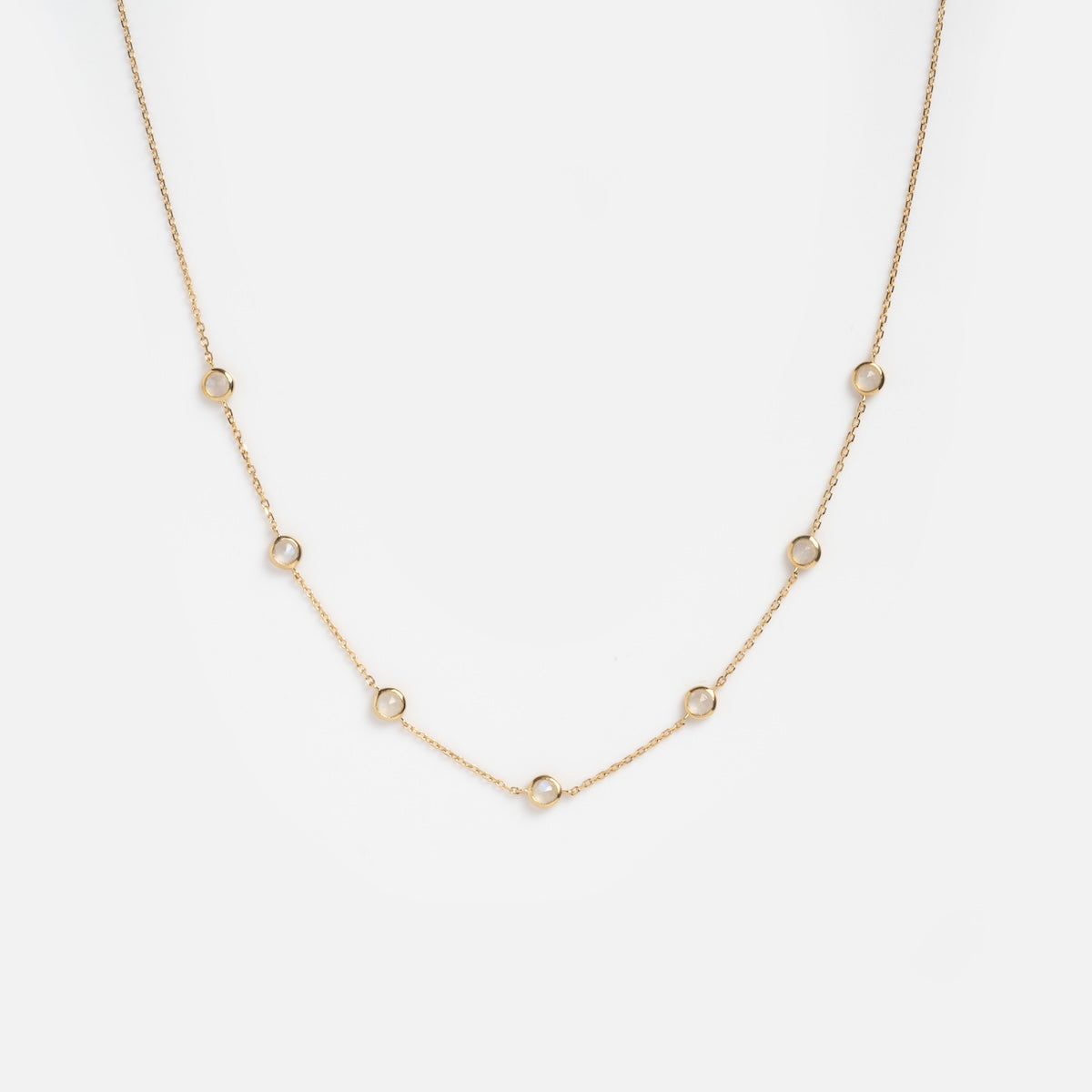 Showcased on a plain white background, the Solid Gold Birthstone Station Necklace Sample features a delicate 9k yellow gold chain with evenly spaced small circular links.
