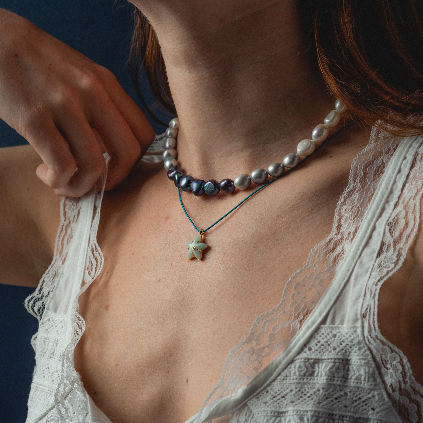 Close-up of a person wearing a beaded necklace with a star pendant.