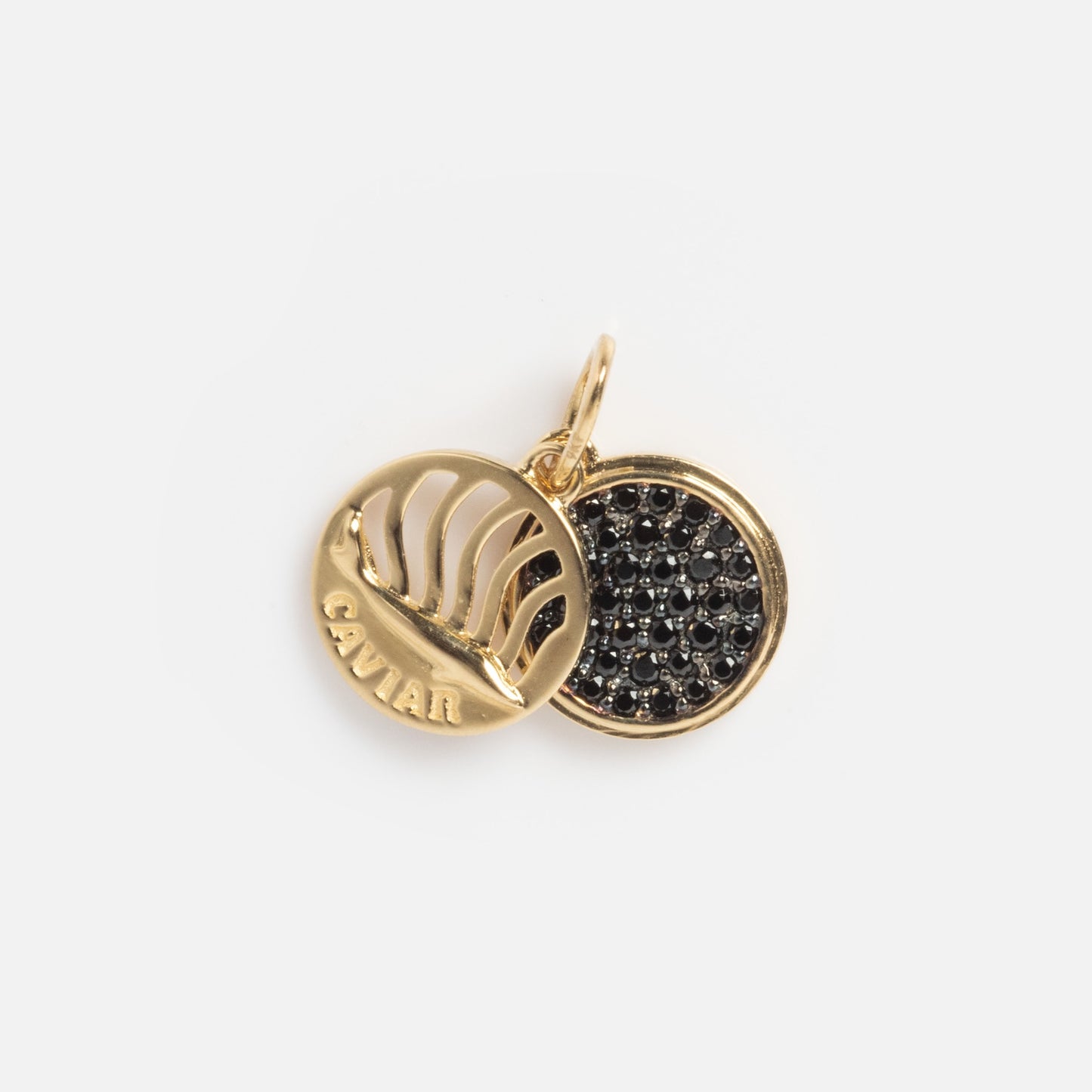 The Solid Gold Caviar Charm Sample features two round pendants: one adorned with black gemstones, the other with cut-out lines and “CAVIAR” engraved at the bottom.