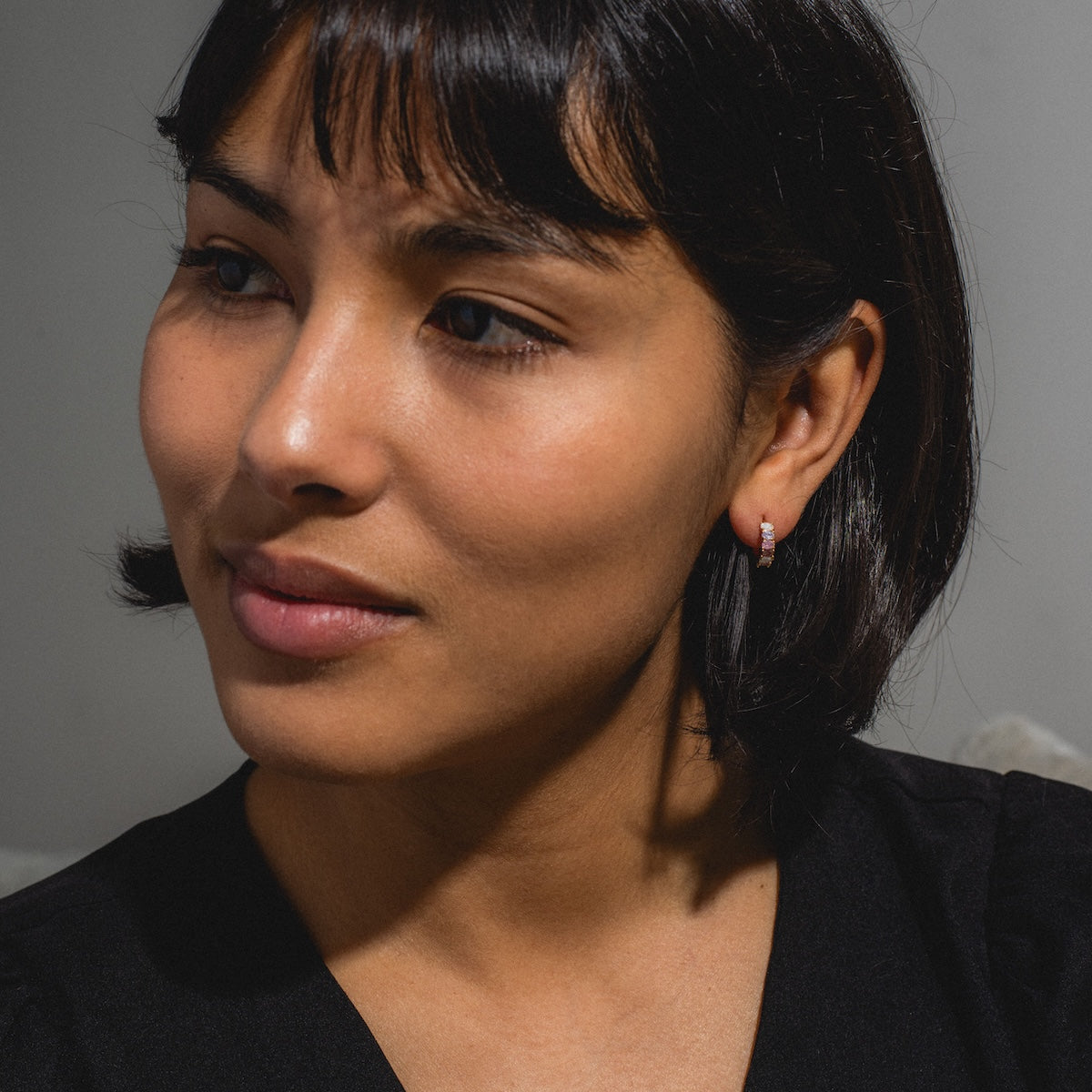 A woman glances sideways, highlighting her pastel earrings and stylish Dreaming About You Hoops.