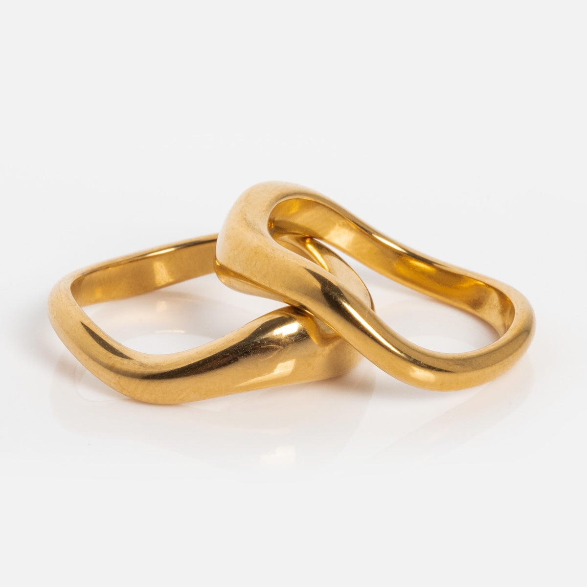 The Curves Ring Set features two gold-plated rings with smooth, wavy, and slightly irregular shapes interlocked on a white background—an elegant choice for stacking ring lovers.