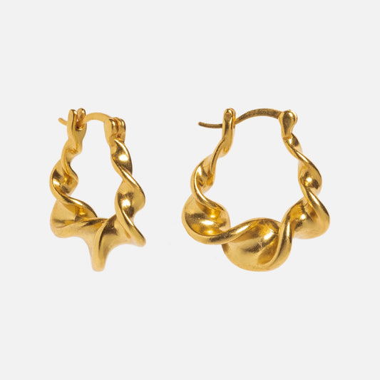The Twisted Hoops are 18k gold earrings featuring a wavy, mismatched design. Displayed against a plain white background, these sculptural pieces share the same organic style.