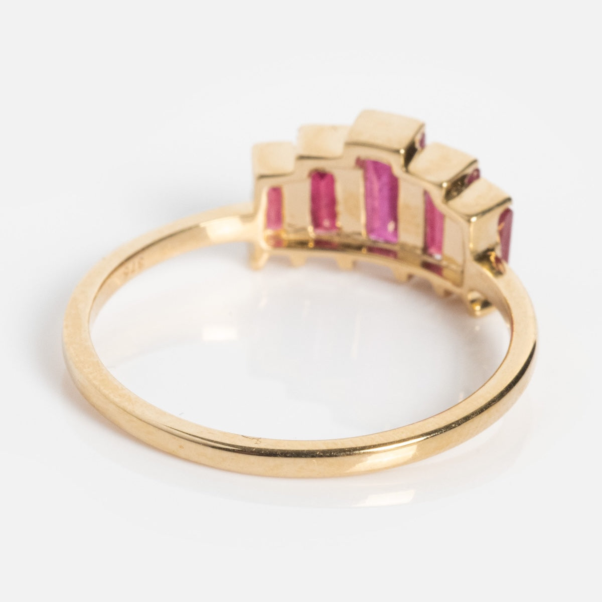 The Solid Gold 2025 July Capsule Art Deco Ruby Statement Ring showcases rectangular pink rubies set vertically on one side, making it a bold statement piece against a white background.
