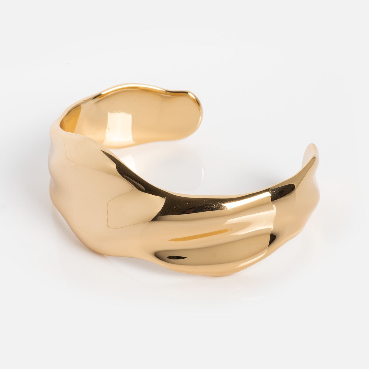 The Wavy Days Cuff is a gold statement bracelet with a wide, wavy design and a smooth, shiny finish, shown on a plain white background.
