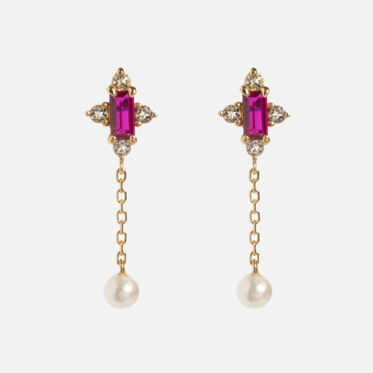 Introducing the Solid Gold 2025 July Capsule Vintage Inspired Ruby Drop Earrings, featuring a vertical ruby gemstone, clear cross-shaped crystals, a delicate gold chain, and a single dangling pearl.