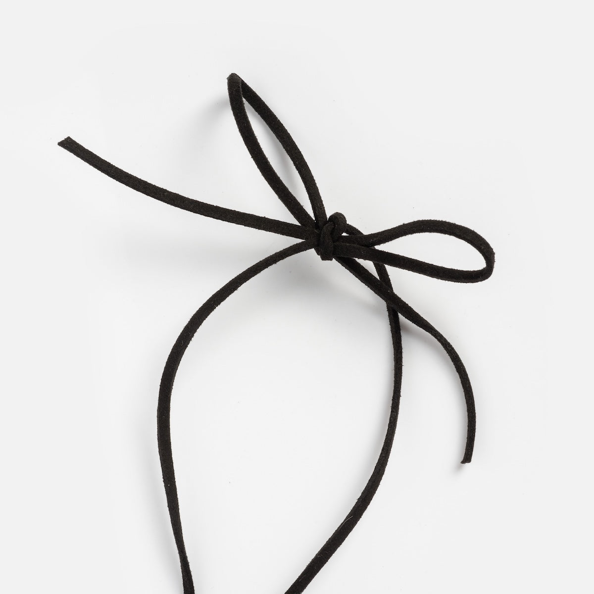 The Passion Necklace features a black vegan suede cord tied in a simple bow, displayed against a plain white background.