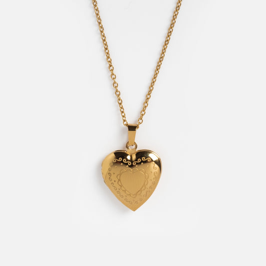 The Daydream Necklace features a gold heart locket pendant with engraved decorative patterns on a matching gold chain, shown against a plain white background.
