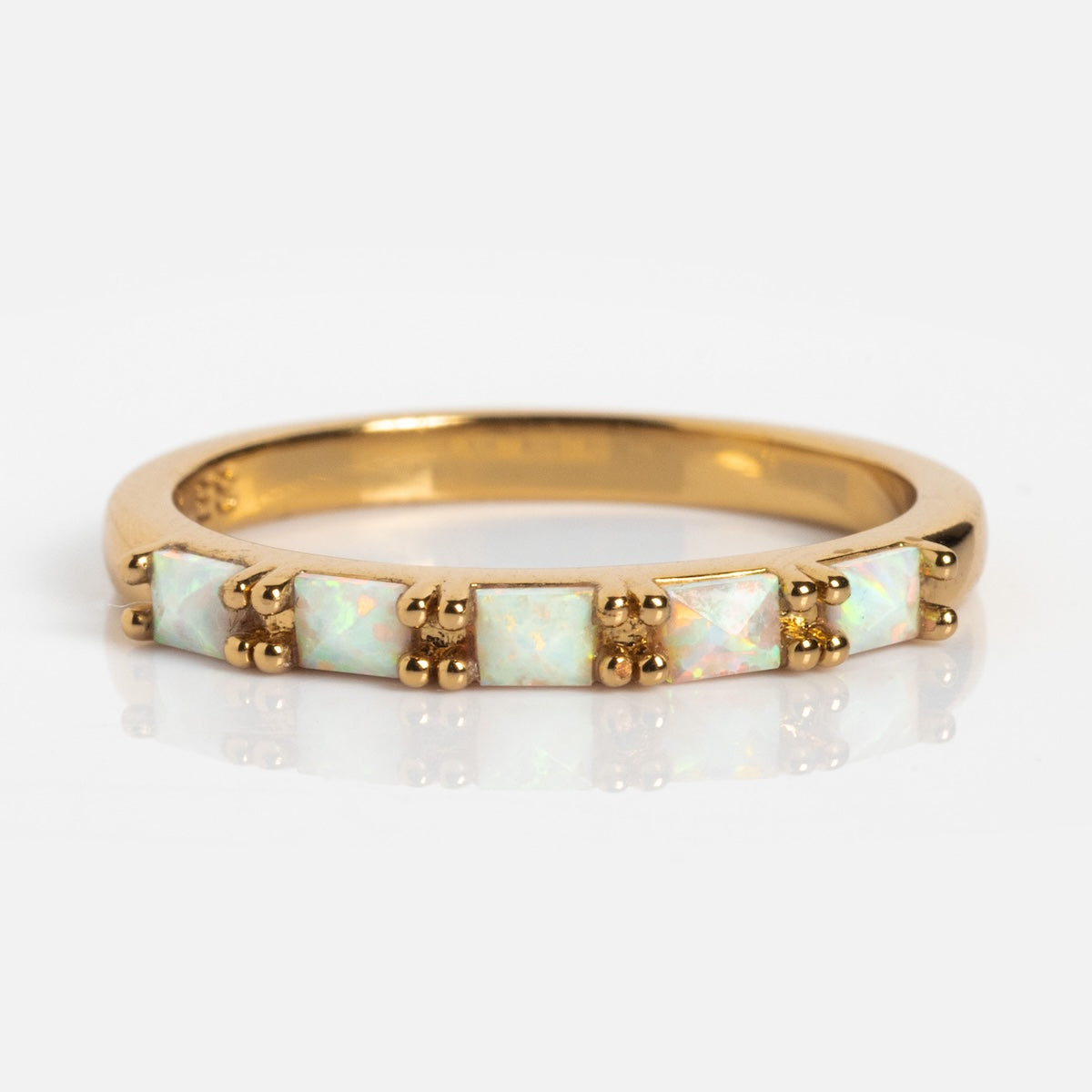 The Opal Baguette Band is a 14k gold plated stacking ring with five square-cut opal stones set in a row, each secured by gold prongs, shown on a white background.