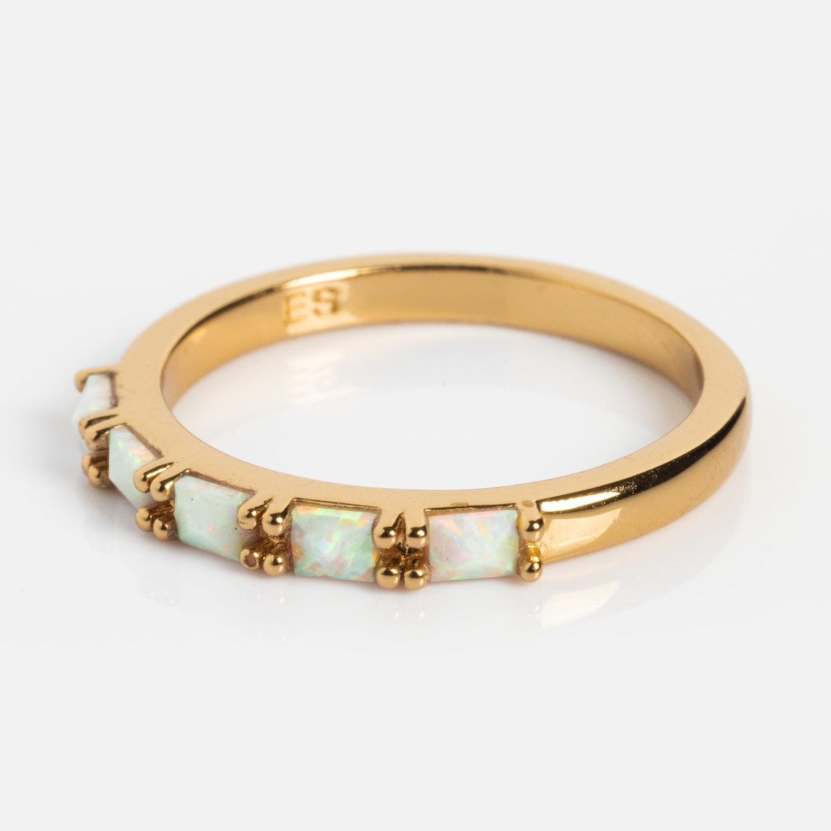 The Opal Baguette Band is a 14k gold plated stacking ring with five square opal stones, each secured by four prongs, set along the band against a plain white background.
