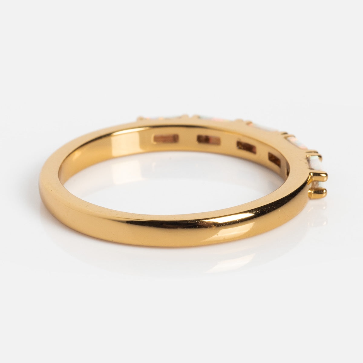 A close-up side view of the Opal Baguette Band, a 14k gold plated ring with a smooth, shiny band and small opal baguettes set along the top edge, perfect for stacking or wearing as an elegant statement against a plain white background.
