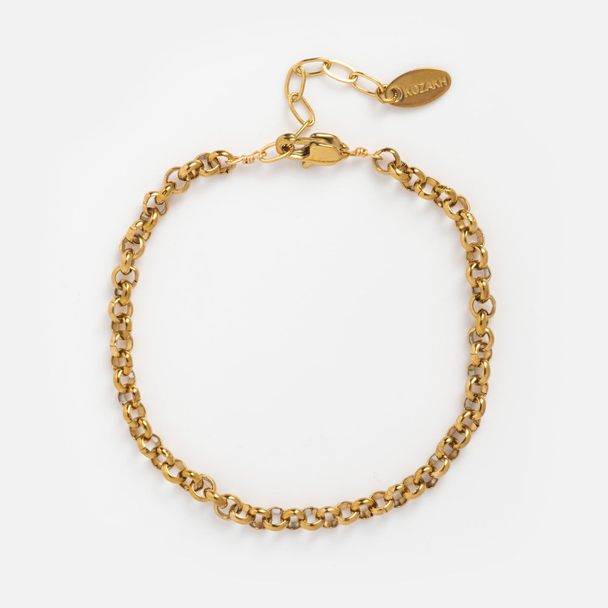 The Baron Bracelet is a gold chain bracelet made of durable stainless steel with round interlocking links, a lobster clasp, and an adjustable extension featuring a KOZAKH-engraved tag on a white background.
