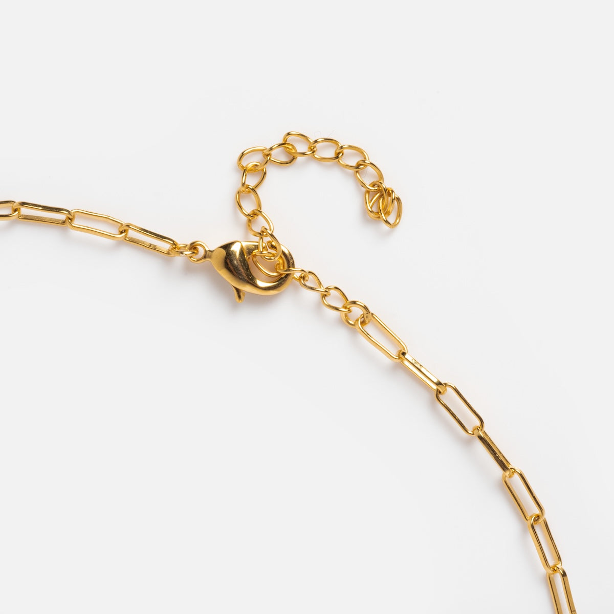 A close-up of the Born to Shine Birthstone Necklace featuring a gold paperclip chain with elongated links, a lobster clasp, and an adjustable extension chain, shown against a plain white background.