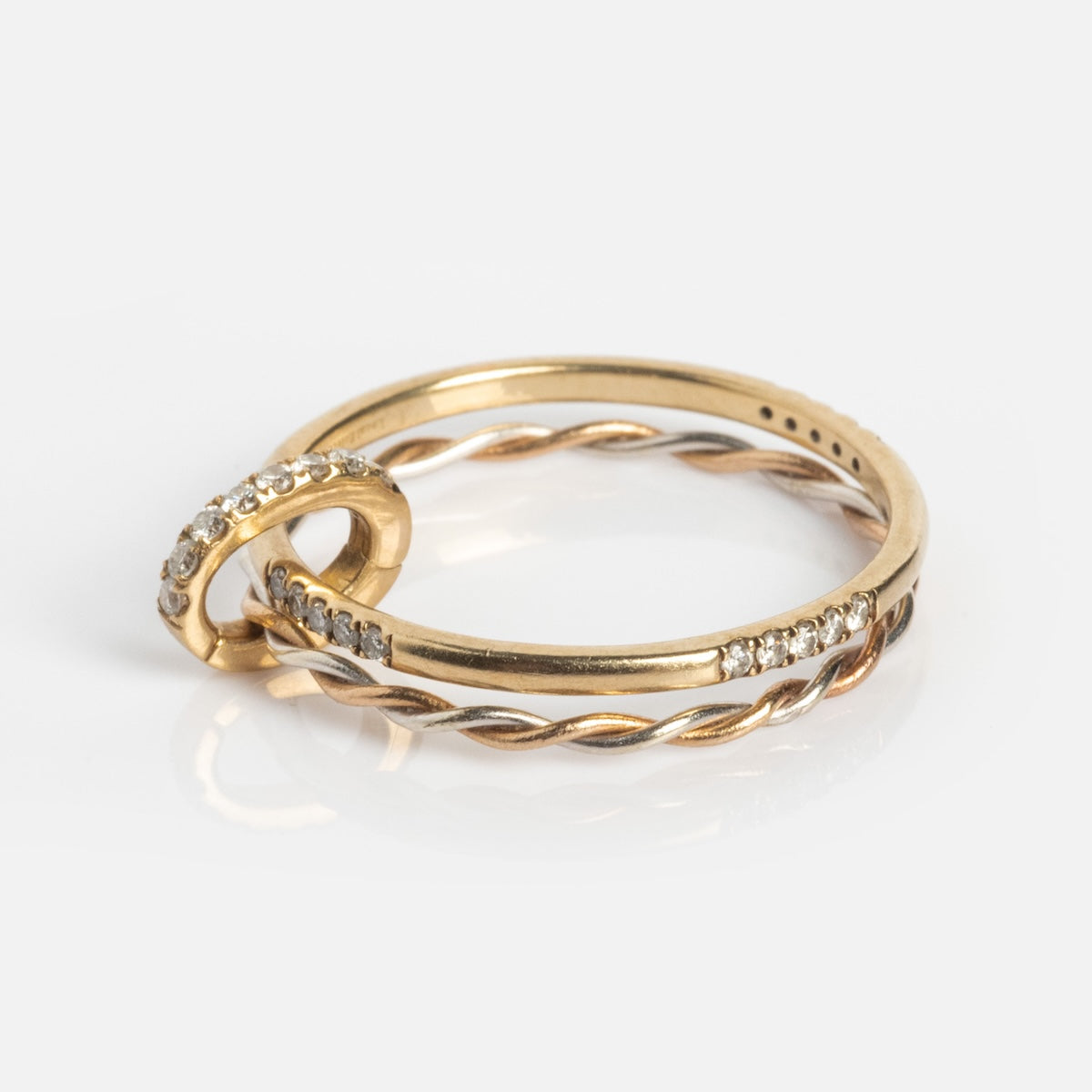 The Solid Gold Ring Clip features a delicate twisted band and a diamond-encrusted loop—ideal for creating your own ring stack, shown on a plain white background.