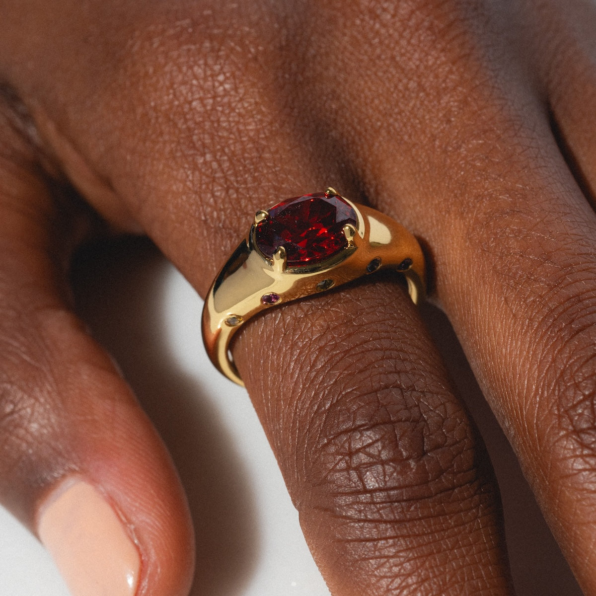 Gold ring with a red gemstone on a person's finger