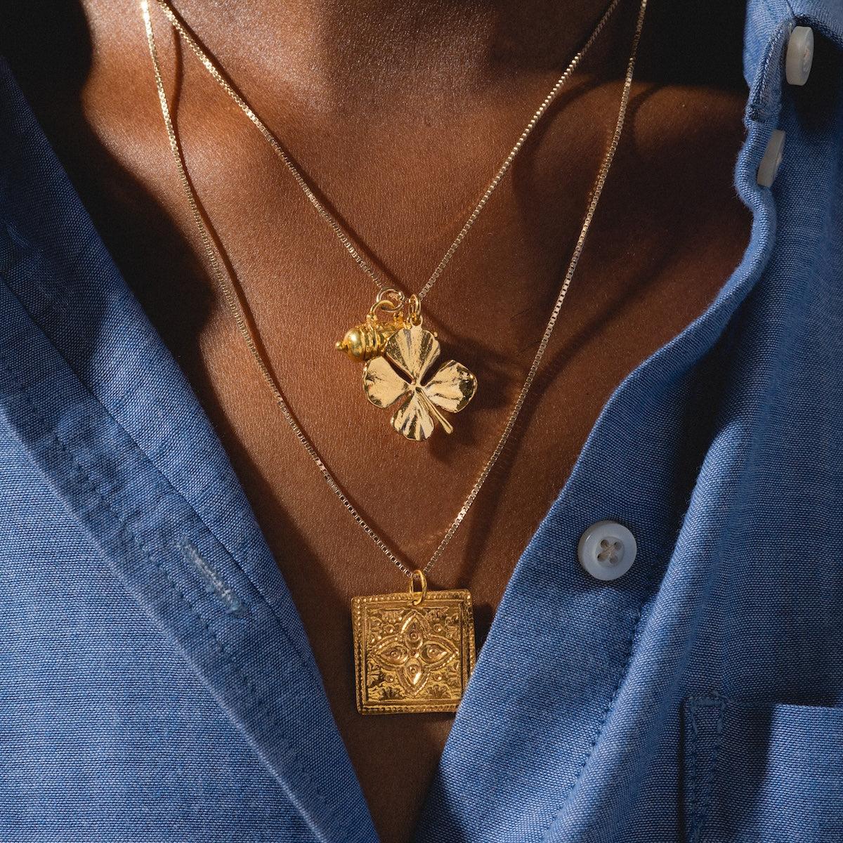 Close up of Tum, Kinara, and four leaf clover charms being worn