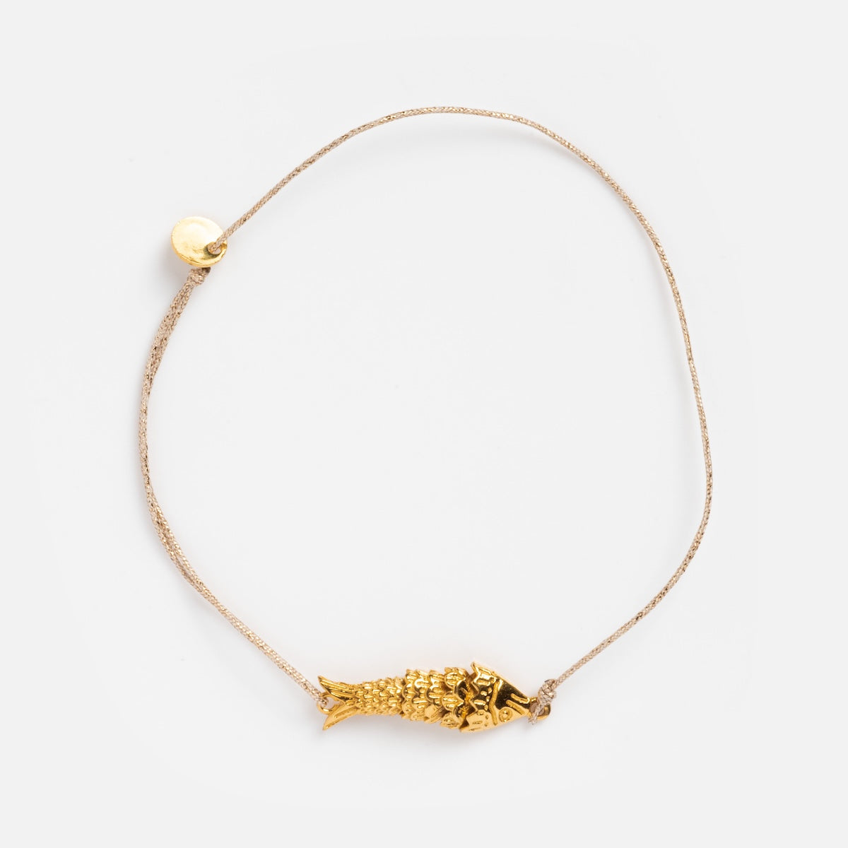 The Sardina Bracelet by Sophie Deschamps Bijoux showcases a thin light cord with a detailed gold fish charm and a small round gold bead, displayed on a plain white background.