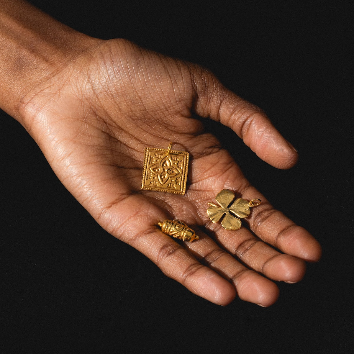Kinara, Tum, and four leaf clover charms in a palm