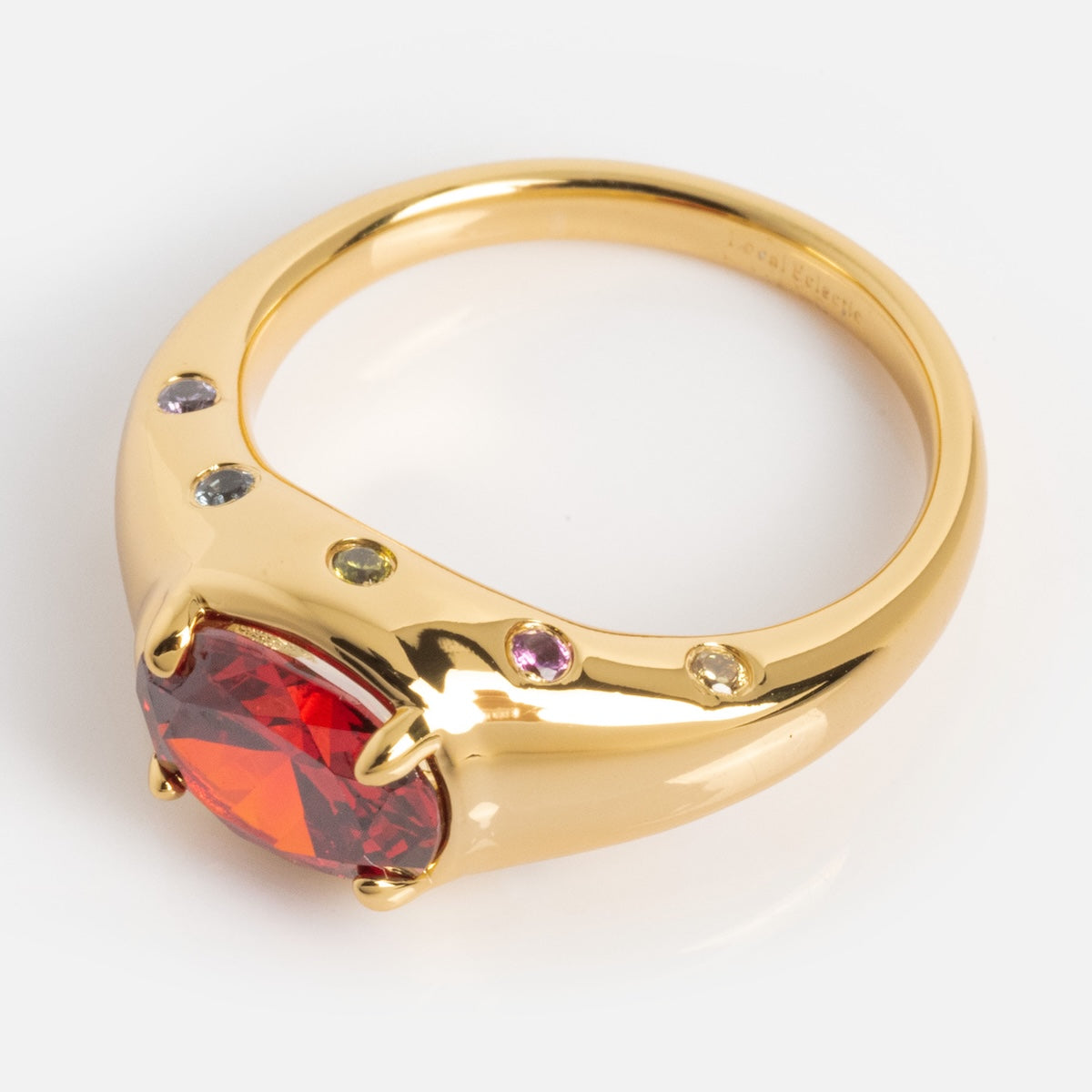 Gold ring with a red gemstone on a white background