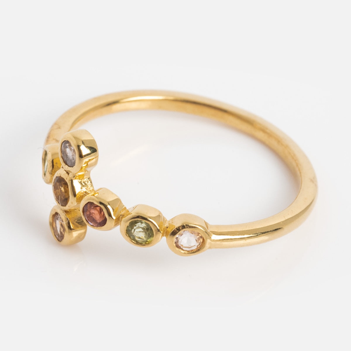 The Notre Dame Ring is yellow gold plated, featuring a cluster of small round multi-color gemstones in hexagonal bezels arranged geometrically on the upper band, shown against a plain white background.