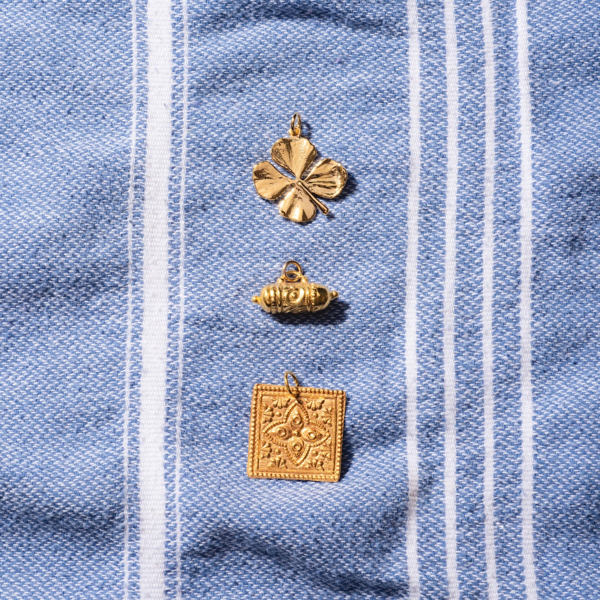 Kinara, Tum, and four leaf clover charms layed on blue and white striped cloth